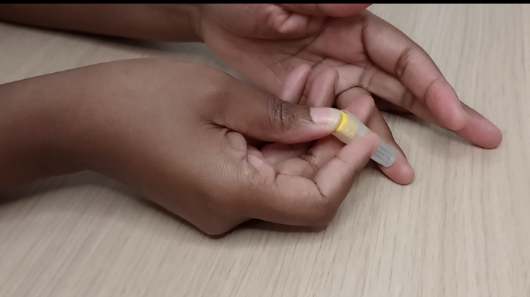 a close up of a hand administering a finger prick blood extraction
